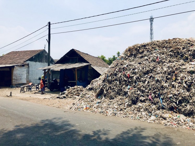 Where's home?: A mound of imported hazardous and contaminated nonhazardous waste is located beside a house in Bangun village, East Java. The village has been inundated by plastic waste imported from Western countries and elsewhere. 