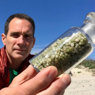 Jace Tunnell, founder of the Nurdle Patrol, holds a bottle of nurdles that litter the beach in Texas. These pellets are the building blocks of plastic products like water bottles, car parts and grocery bags. (Photo courtesy of Jace Tunnell)