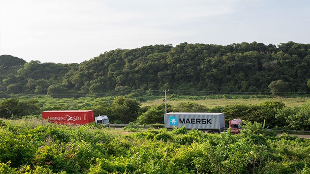 A truck carrying a Hamburg Süd-branded container follows another truck hauling a Maersk-branded container. 
(Photo: A.P. Møller - Mærsk)