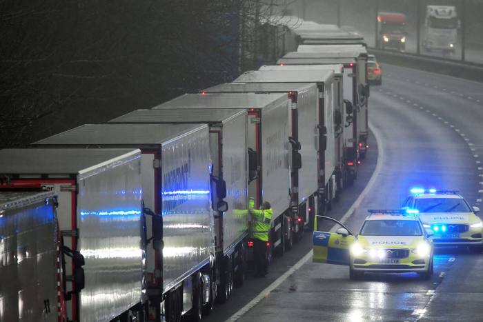 A police officer knocks on the cabin of one of the lorries parked on the M20 motorway in Kent as part of Operation Stack