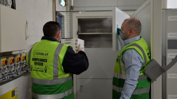 Specially trained members of the Cold Chain warehouse operations team transfer boxes of Pfizer/BioNtech vaccine vials to ultra low temperature freezers. Photograph: Alan Betson