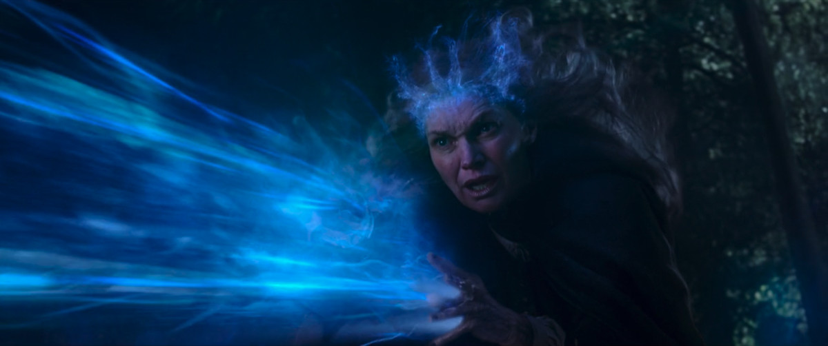 Agatha Harkness’ mother blasts blue magic from her hands as it gives her a blue magic crown in WandaVision. 